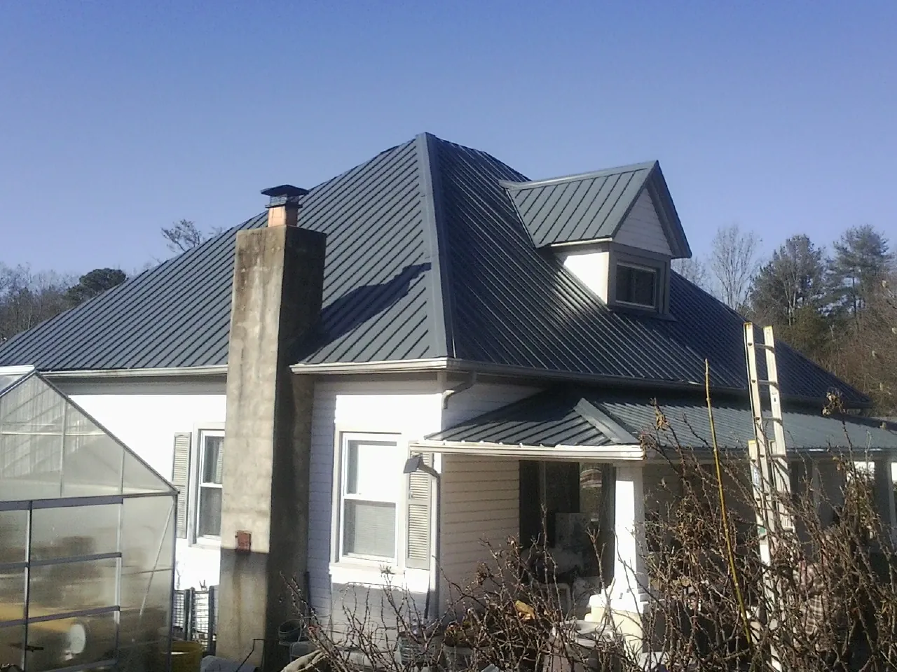 Dark blue standing seam metal roof on a white farmhouse with dormer — Slate & Tile Roof Repair by Roofing Brothers in West Shokan