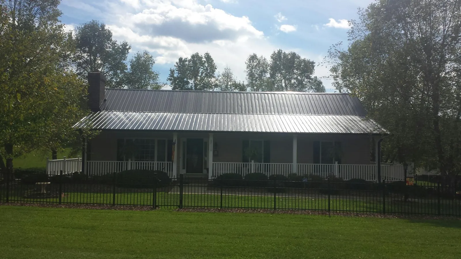 Gray metal roof on a brick ranch with a full width front porch — Gutter Guard Installation work by our crew in West Shokan