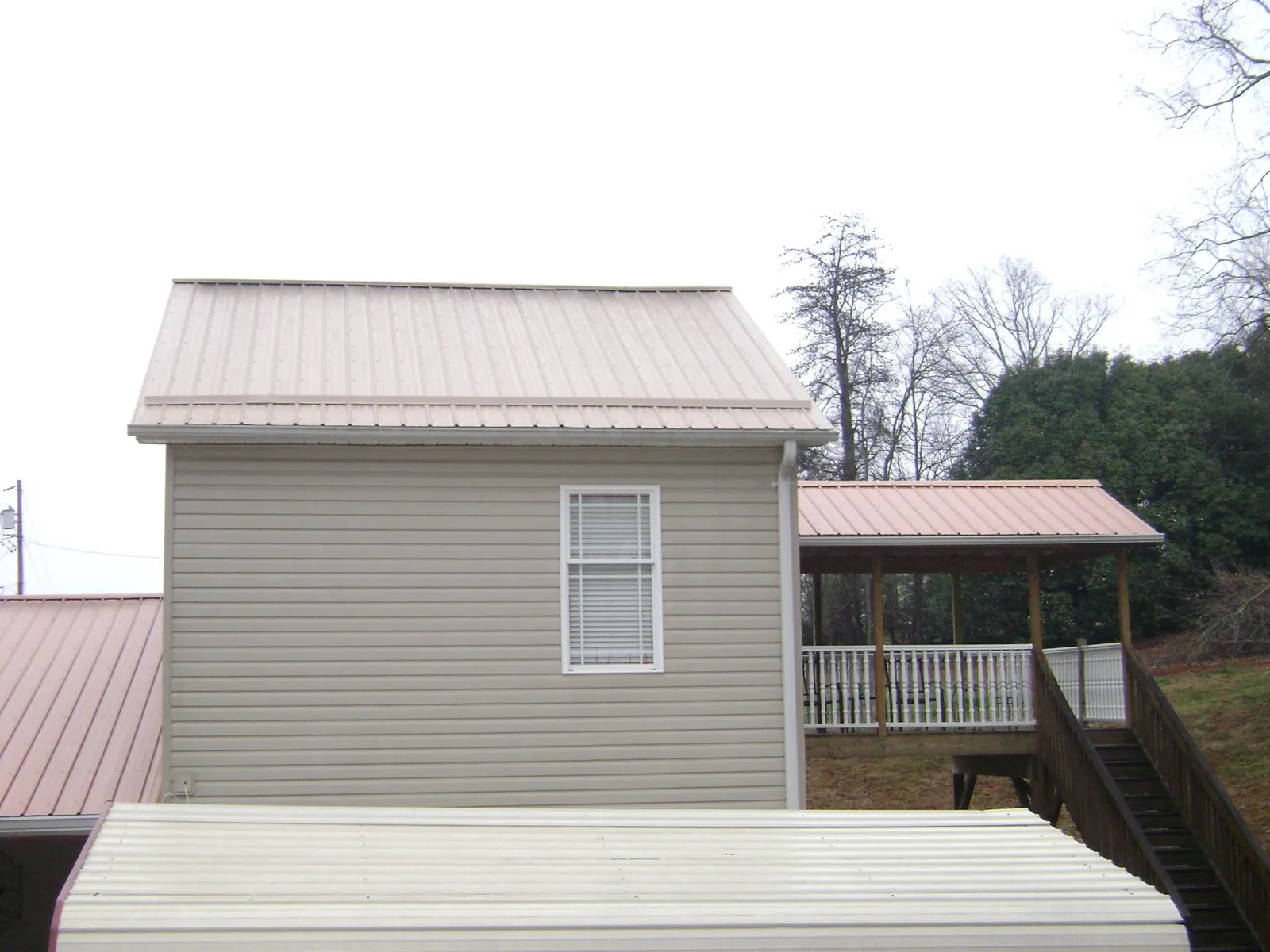 Tan metal roofs on a two story addition and attached porch, from a Roof Replacement job in West Shokan