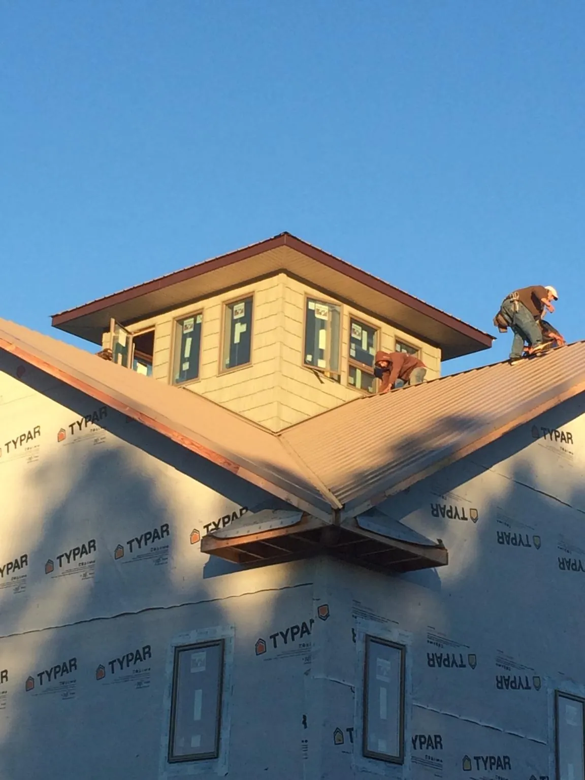 Roofers working around a rooftop cupola on a new metal roof at sunset — Roof Waterproofing in West Shokan by Roofing Brothers